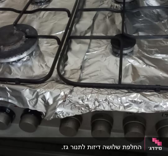 כיריים גז מכוסות בנייר כסף עם כפתורי שליטה